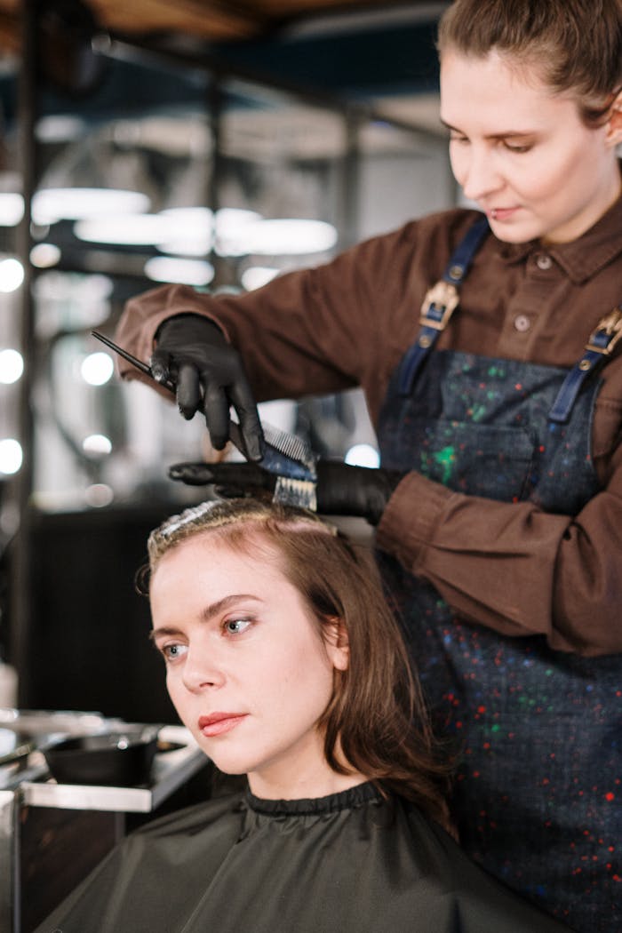 A hairstylist expertly dyes a woman's hair in a contemporary salon setting, highlighting beauty and care.